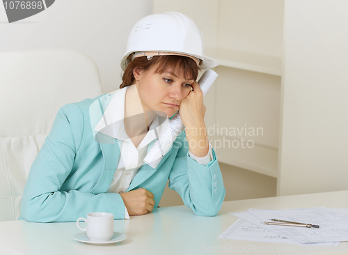 Image of Woman engineer sits on workplace at office and mourns