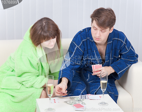 Image of Guy and girl play cards on money