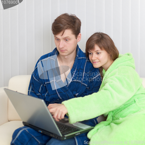 Image of Guy and woman sit on sofa with laptop