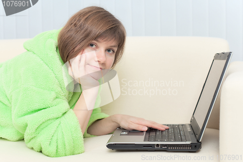 Image of Portrait of young woman in dressing gown with laptop