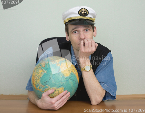 Image of Young man in a sea cap of captain with globe