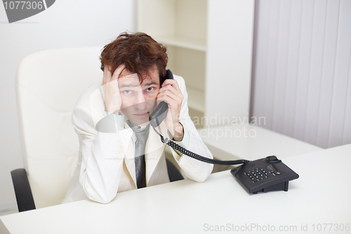 Image of Tired businessman tensely speaks on phone