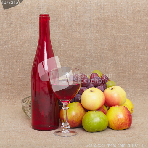 Image of Still-life - red bottle of wine and fruit against a canvas