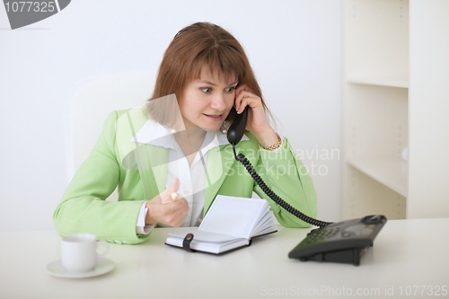 Image of Young beautiful woman - secretary emotionally speaks on phone