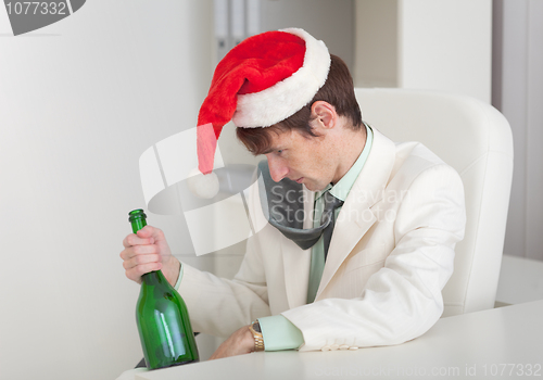 Image of Drunken man in Christmas cap with bottle in a hand