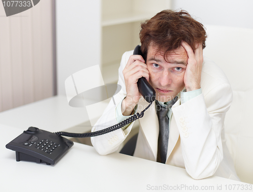 Image of Person excited communicates by phone sitting at a table