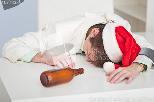 Image of Drunk person in a Christmas cap lies on white table