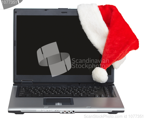 Image of New Year s laptop with blank screen and santa cap