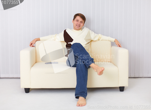 Image of Happy guy sits on sofa and watches TV