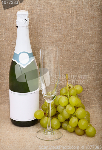 Image of Still-life from bottle of sparkling wine, empty glass and grapes