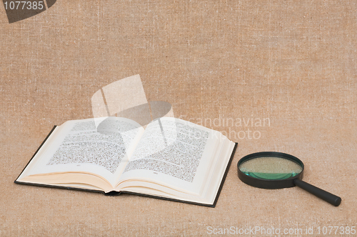 Image of Composition from opened book and magnifier lying on canvas