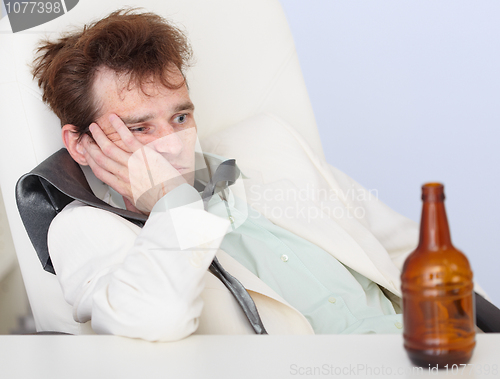 Image of Young sad businessman sits with an empty bottle