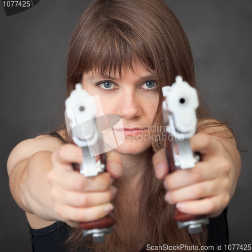 Image of Serious girl aims from two pistols close up