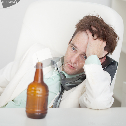 Image of Person suffers from hangover sitting at a table