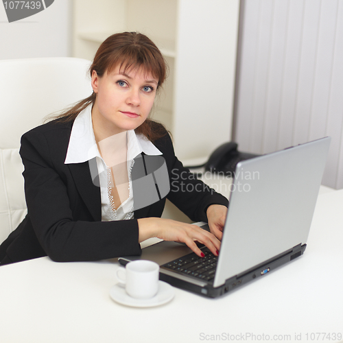 Image of Young beautiful woman with laptop sits at a table