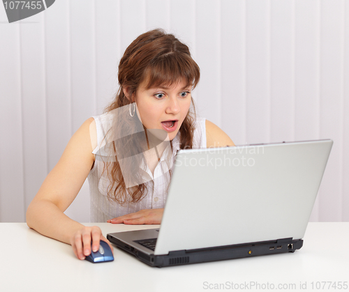 Image of Young beautiful woman funny emotionally looking in laptop screen