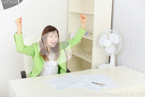 Image of Exulting young woman sits at a table