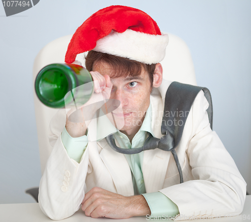 Image of Drunk man in Christmas cap plays with bottle