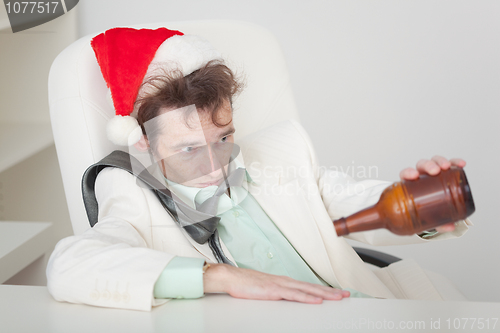 Image of Drunken person in Christmas cap with bottle in a hand