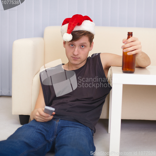 Image of People in christmas hat sits on a floor with beer