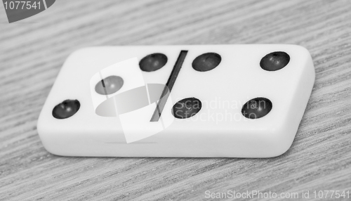 Image of One dominoes lies on wooden surface close up