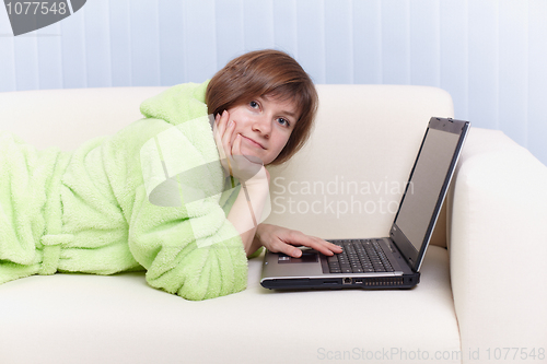 Image of Young girl in green dressing gown on sofa with computer