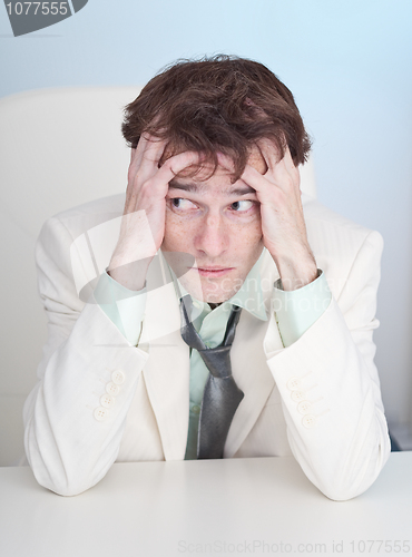 Image of Uneasy businessman sits at a table