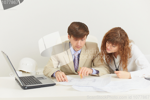 Image of Two young businessmen work with documents