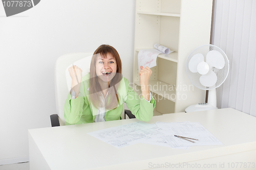 Image of Exulting young woman at office on workplace