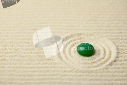 Image of Green big glass drop on a sand surface