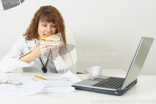 Image of Businesswoman hurries up to eat without coming off work