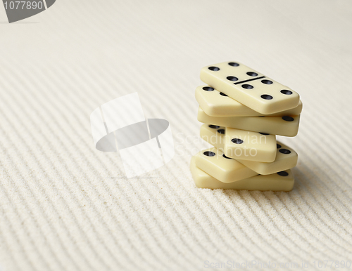 Image of Dominoes pile on surface of sand - an abstract composition