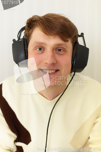 Image of Cheerful guy with big ear-phones on a head