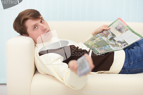 Image of Man with newspaper and remote control