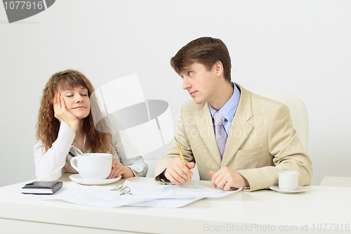 Image of Woman falls asleep sitting at table with huge cup of coffee