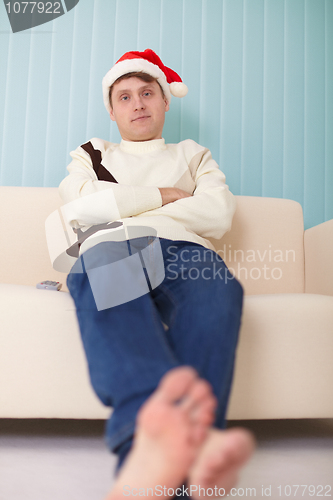 Image of Person in Christmas cap sits on sofa