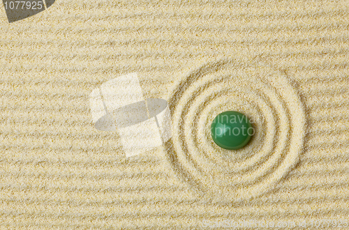 Image of Green stone on surface of yellow sand