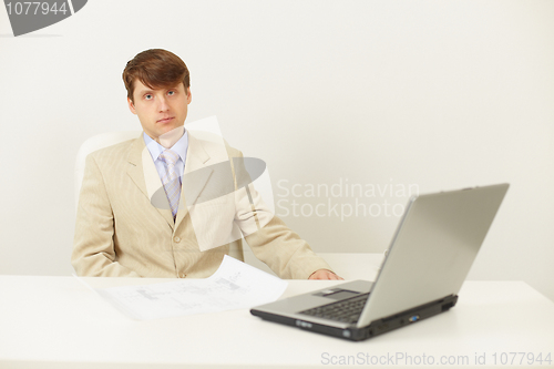 Image of Serious man in light jacket sits at a table