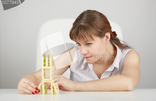 Image of Young woman plays from dominoes sitting at table