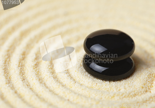 Image of Two black stones put in a pile on sand