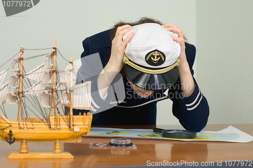 Image of Woman in uniform of sea captain concentrated thinks over a map
