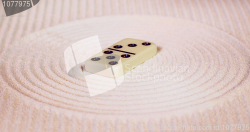 Image of Dominoes on sand in rock garden