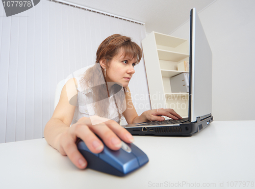 Image of Young woman with concentration works in Internet