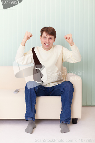 Image of Person on sofa watches football on TV