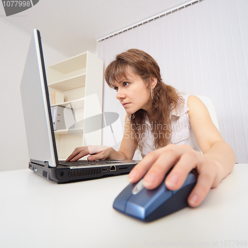 Image of Young woman with concentration works in Internet on computer