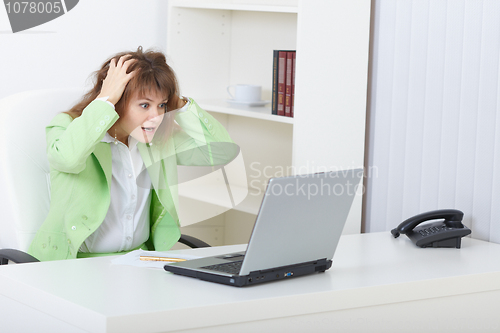 Image of Scared woman sits on workplace with laptop