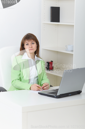 Image of Serious girl sits on workplace with laptop