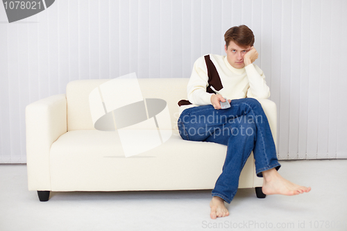 Image of Young man misses sitting on sofa at the TV