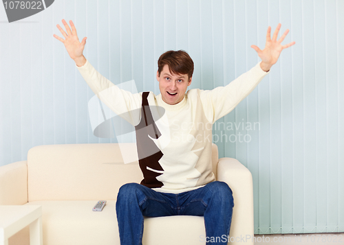 Image of Young man exults sitting on sofa - sports fan