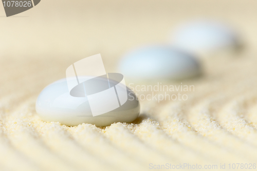 Image of Three white drops on surface of yellow sand